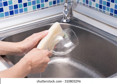 Cleaning a wine glass with a sponge in the sink