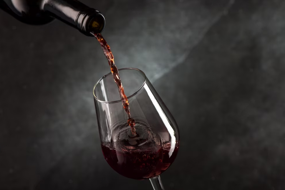 pouring wine into a wine glass in front of a marble black wall