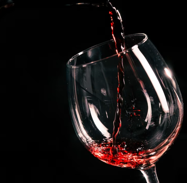 photo in motion of pouring wine into a wine glass and a black background behind
