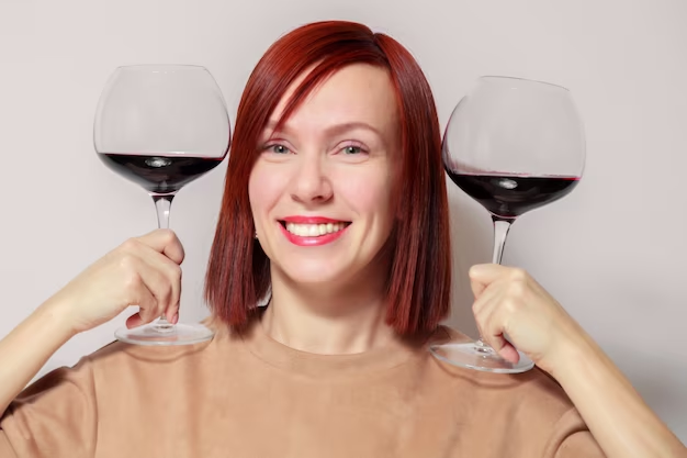 Woman with red hair holding glasses and smiling
